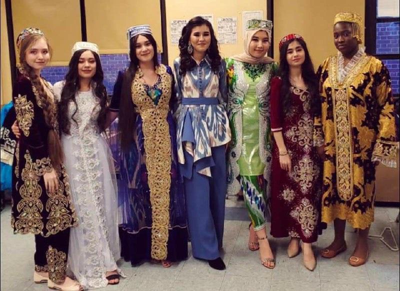 Young women in embroidered traditional gowns and headdresses posing in a school corridor